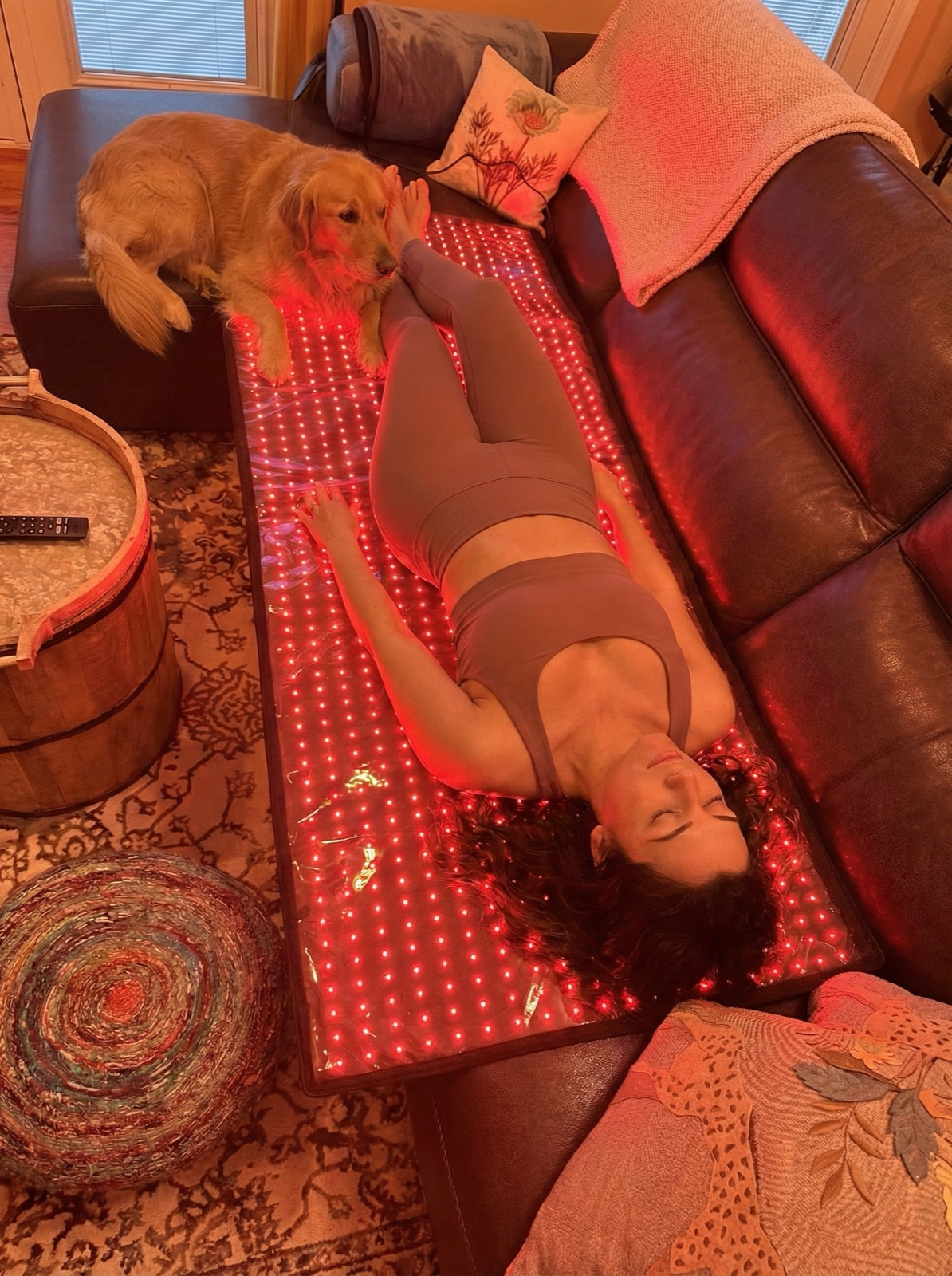 A woman and her dog beside the Red Light+ Mat