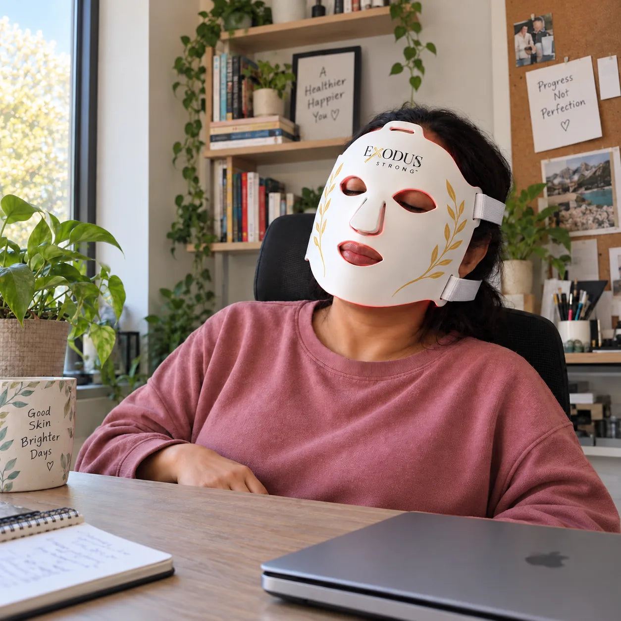A woman taking a break at her desk wearing the white Red Light+ Face Mask