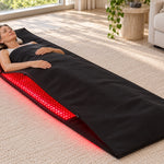 A woman lying inside the Red Light+ Laser Blanket, head out, awake, in morning light