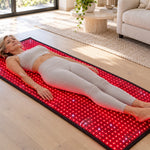 A woman lying on the Red Light+ Laser Mat on a living room floor in daylight