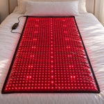 The Red Light+ Laser Mat lit on a made bed in morning light