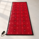 Red Light+ Laser Mat lit on a studio floor, the laser modules showing as brighter points down the center and in pairs